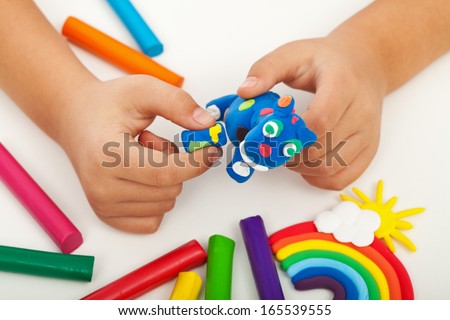 Child playing with colorful clay making animal figures - closeup on hands