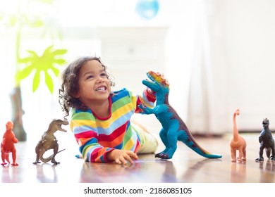 Child playing with colorful toy dinosaurs. Educational toys for kids. Little boy learning fossils and reptiles. Children play with dinosaur toys. Evolution and paleontology game for young kid.