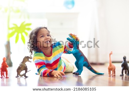 Child playing with colorful toy dinosaurs. Educational toys for kids. Little boy learning fossils and reptiles. Children play with dinosaur toys. Evolution and paleontology game for young kid.