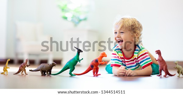 Child playing with colorful toy dinosaurs.\
Educational toys for kids. Little boy learning fossils and\
reptiles. Children play with dinosaur toys. Evolution and\
paleontology game for young\
kid.