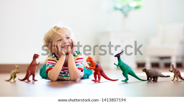 Child playing with colorful toy dinosaurs.\
Educational toys for kids. Little boy learning fossils and\
reptiles. Children play with dinosaur toys. Evolution and\
paleontology game for young\
kid.