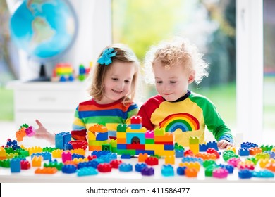 Child playing with colorful toys. Little girl and funny curly baby boy with educational toy blocks. Children play at day care or preschool. Mess in kids room. Toddlers build a tower in kindergarten.
