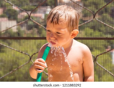 Child Playing And Cooling Off From The Heat With Water And With A Hose