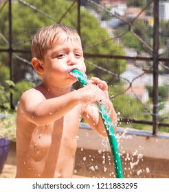 Child Playing And Cooling Off From The Heat With Water And With A Hose