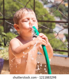 Child Playing And Cooling Off From The Heat With Water And With A Hose