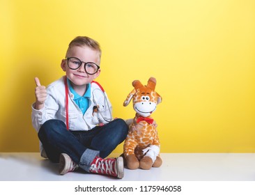 Child playing doctor with toy animal giraffe. Happy smiling kid boy with thumb up at home or daycare. Pediatrician for preschool and kindergarten kids. Pediatric, healthcare and people concept.