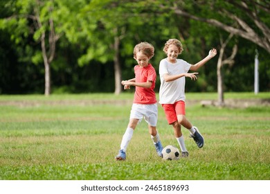 Child playing football. Kids play soccer on outdoor pitch. Little boy kicking ball in summer park. Healthy activity for young children. School sport club team. Football junior league. - Powered by Shutterstock