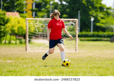 Child playing football. Kids play soccer on outdoor pitch. Teenage girl kicking ball in summer park. Healthy activity for young children. School sport club team. Football junior league. - Powered by Shutterstock