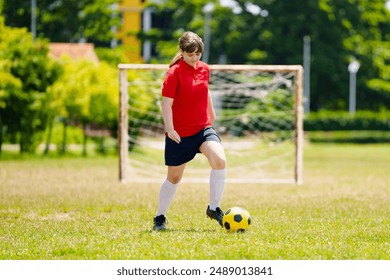 Child playing football. Kids play soccer on outdoor pitch. Teenage girl kicking ball in summer park. Healthy activity for young children. School sport club team. Football junior league. - Powered by Shutterstock