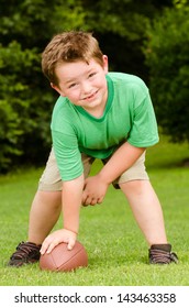 Child Playing With Football Outdoors In Yard