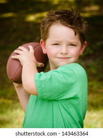 Child Playing With Football Outdoors In Yard