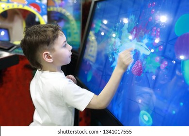 Child Playing Game On Large Touch Screen In Amusement Park