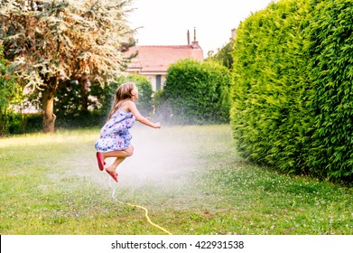 Child playing with garden sprinkler, jumping over - Powered by Shutterstock