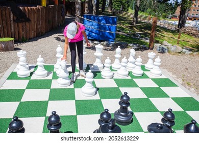 Child Playing Giant Outdoor Chess Set In Park.