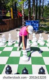 Child Playing Giant Outdoor Chess Set In Park.