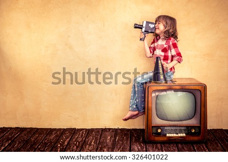 Child playing at home. Kid making a film with retro camera. Cinema concept