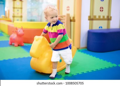 Child Playing With Hopping Horse. Indoor Activity Toys For Kids. Kindergarten Or Preschool Play Room. Toddler Kid At Day Care Playground. Swing Pony For Children. Baby Boy With Toy At Daycare.