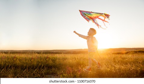 Child playing with a kite while running on meadow, sunset, in summer day.  Funny time with family. Happy little boy launch a kite.  - Shutterstock ID 1100716370
