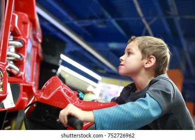 Child playing in motorcycle simulator at indoor playground