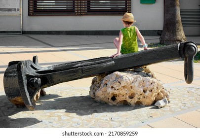 Child Playing In The Olympic Port With An Anchor In The Context Of Having Vacations At School And Going For A Walk With His Parents Because He Is Bored At Home.