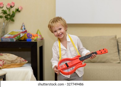 Child Playing On A Guitar. Home Party