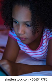 Child Playing On Her Tablet While Lying On Her Bed