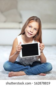 Child Playing On Ipad Sitting On A Carpet At Home