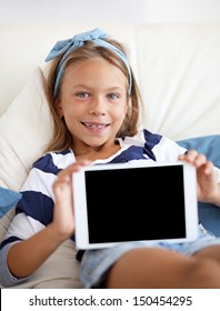 Child playing on ipad tablet pc on the sofa at home