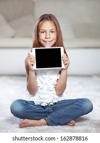 Child Playing On Ipad Tablet Pc Sitting On A Carpet At Home