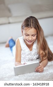 Child Playing On Ipad Tablet Pc Sitting On A Carpet At Home