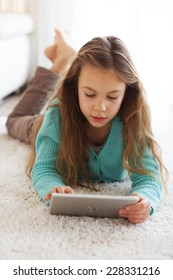 Child Playing On Ipad Tablet Pc Sitting On A Carpet At Home