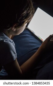 Child Playing On A Tablet In Bed