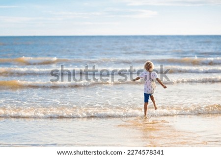 Child playing on tropical beach. Little boy with bucket and spade at seashore. Family summer vacation. Kid building sandcastle. Kids search for shells and play. Water and sand fun for children. 