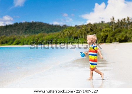 Child playing on tropical beach. Little boy digging sand at sea shore. Family summer vacation. Kids play with water and sand toys. Ocean and island fun. Travel with young children. Asia holiday.