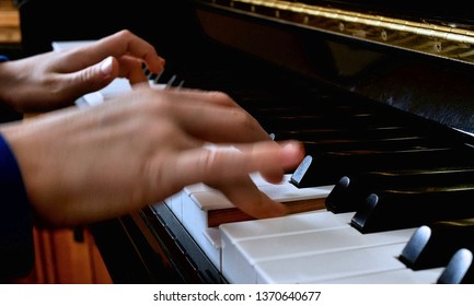 Child Playing Piano. Close Up Side View Of Blurred Fast Moving Young Hands And Fingers Playing A Song On The Keys Of An Upright Shiny Black Piano.