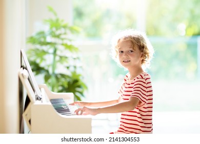 Child playing piano. Kids play music. Classical education for children. Art lesson. Little boy at white digital keyboard. Instrument for young student. Music class in school or at home.