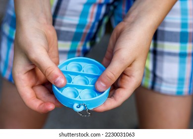 Child playing with pop it sensory antistress toy. Stress relief fidget in hands of a child. Mental health and anxiety concept. Close up - Shutterstock ID 2230031063