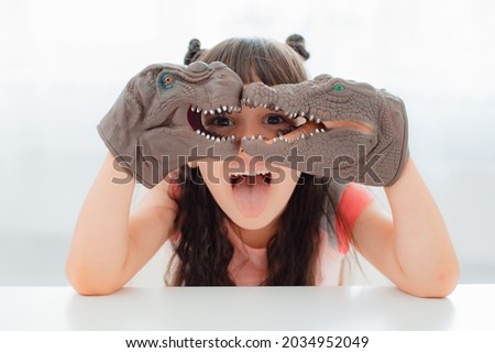 Child playing with with rubber hand-clad toys dinosaurs. Educational developing role-playing game kids. Children girl emotionally play with dinosaur toys. Evolution paleontology game for young kid.