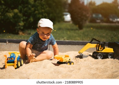 Child Playing In Sandbox. Little Boy Having Fun On Playground In Sandpit. Outdoor Creative Activities For Kids. Summer And Childhood Concept.