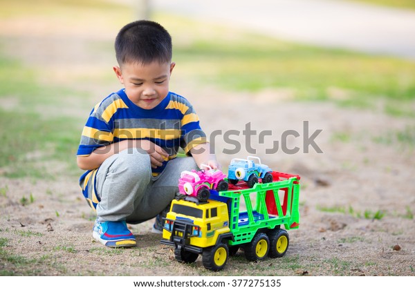 Child playing in\
sandpit with toy truck\
car