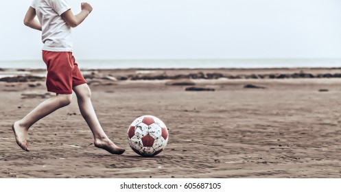 Child playing soccer on the beach