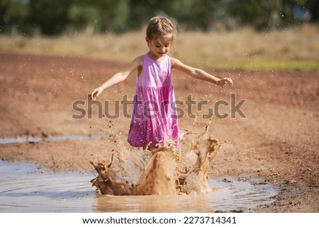 Child Playing and Splashing in Muddy Puddle