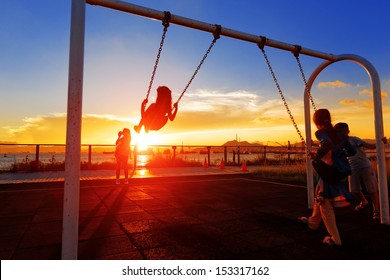 child playing swing against sunset