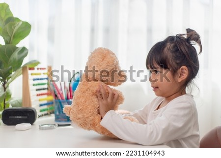 Child playing with teddy bear. Asian little girl hugging his favorite toy. Kid and stuffed animal at home. 