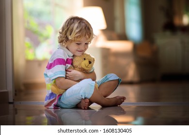 Child playing with teddy bear. Little boy hugging his favorite toy. Kid and stuffed animal at home. Toddler sitting on the floor of living room with big window at sun set. Kids play indoors. - Powered by Shutterstock