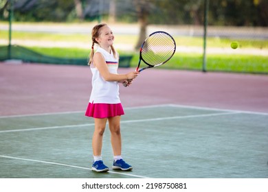 Child Playing Tennis On Indoor Court. Little Girl With Tennis Racket And Ball In Sport Club. Active Exercise For Kids. Summer Activities For Children. Training For Young Kid. Child Learning To Play.