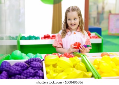 Child playing in toy shop or restaurant. Educational toys and role game for kids. Kindergarten or preschool play room. Toddler kid at day care playground. Grocery store or supermarket for children.