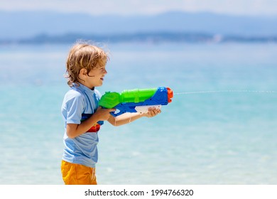 Child Playing With Toy Water Gun. Vacation And Beach Fun. Kids Run And Play With Plastic Pistol On Tropical Island Resort. Family Summer Holiday Activity At The Sea. Travel With Children. 