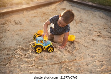 Child Playing With Toys In Sandbox. Little Boy Having Fun On Playground In Sandpit. Outdoor Creative Activities For Kids. Summer And Childhood Concept.