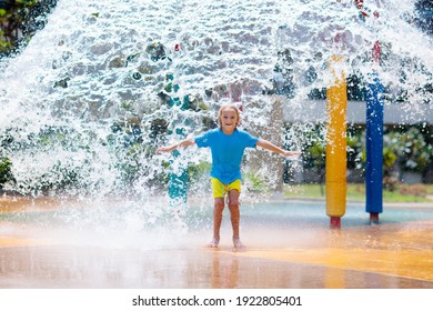 Child Playing Under Tip Bucket In Water Park. Kids Play With Splash Dump Bucket. Family Fun In Amusement Center On Hot Summer Day. Sun Protection For Children. Water Slides For Kid.